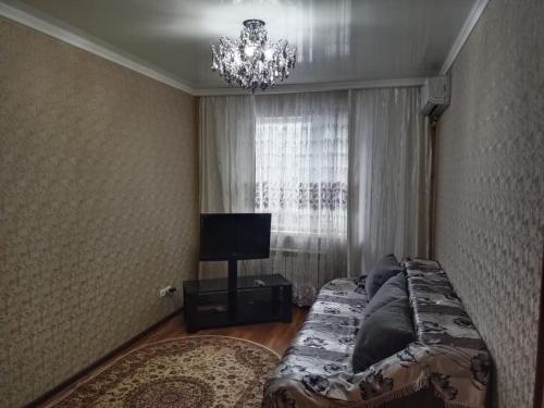 - une chambre avec un lit et un lustre dans l'établissement Квартира, à Astana