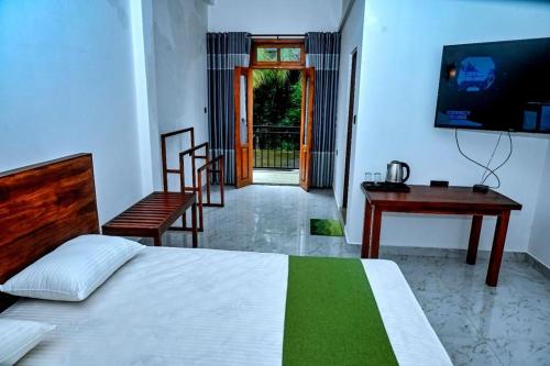 Dormitorio con cama, escritorio y TV en Emerald Home Stay, en Anuradhapura