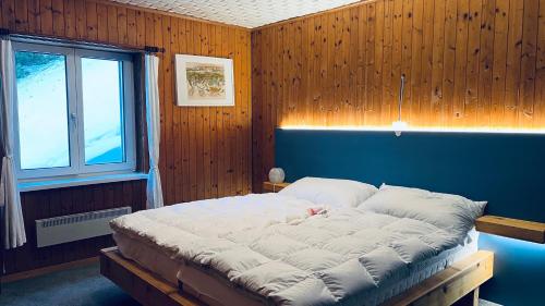 ein großes Bett in einem Zimmer mit Fenster in der Unterkunft Chalet Schwendihus - CharmingStay in Flumserberg