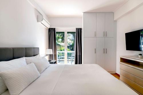 een witte slaapkamer met een groot bed en een televisie bij Boutique77 Luxury Apartment in Athene