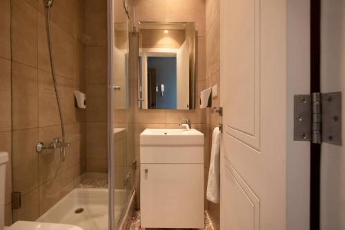 ein Bad mit einem Waschbecken und einer Dusche mit einem Spiegel in der Unterkunft Em Shadi's Studio in Mar Mikhael in Beirut