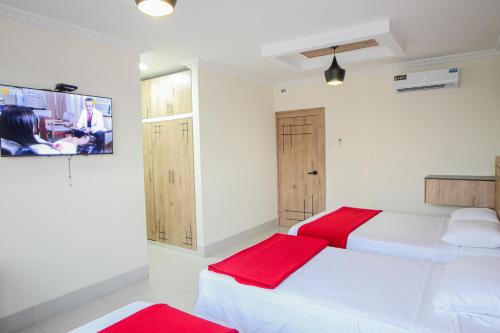 a bedroom with two beds and a tv on the wall at Hotel Murali - Cerca del Aeropuerto de Guayaquil in Guayaquil