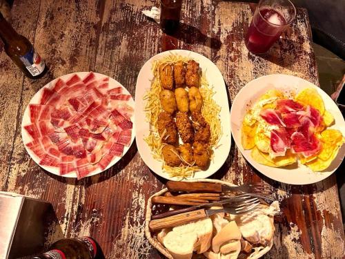 four plates of food on a wooden table at APARTAMENTOS TURíSTICOS MONTASOL 2 in Montánchez