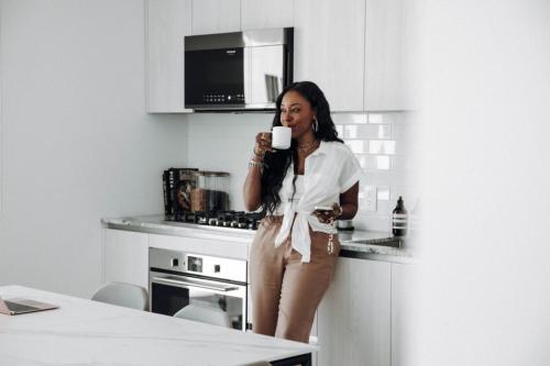 a woman standing in a kitchen holding a cup of coffee at Level Long Beach - East Village in Long Beach