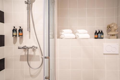een badkamer met een douche en handdoeken op een plank bij Villa Camille Hotel & Spa in Banyuls-sur-Mer