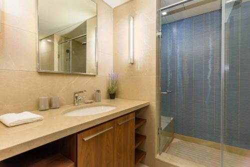 een badkamer met een wastafel en een glazen douche bij Solidere Tune 1Bedroom Apartment At Kantari Beirut in Beiroet