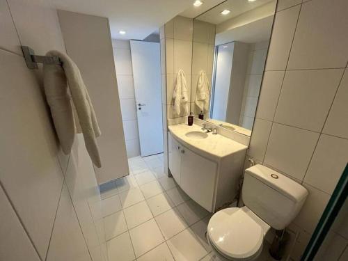 a bathroom with a toilet and a sink and a mirror at Lindo Loft Beira-Mar na Vitória in Salvador