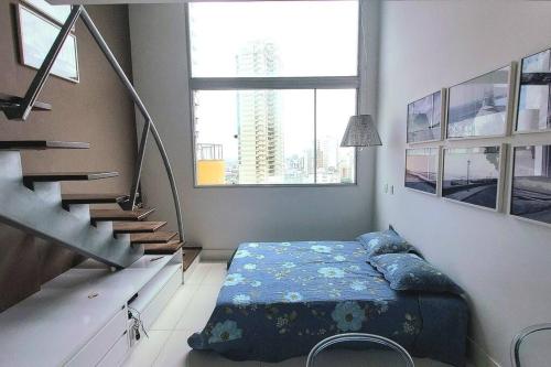 a bedroom with a bed with pillows and a staircase at Lindo Loft Beira-Mar na Vitória in Salvador