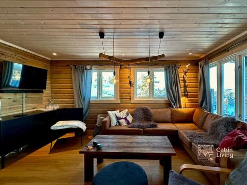 sala de estar con sofá y mesa en Cozy cabin with incredible views and sauna, en Lampeland