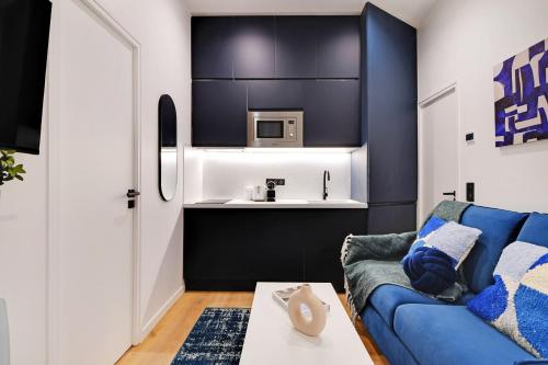 un salon avec un canapé bleu et une cuisine dans l'établissement Intimate apartment - 1BR-2P - Parc des Princes, à Paris