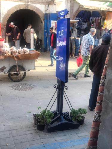 a sign in a market with potted plants on a street at Hôtel Riad Gnaoua in Essaouira