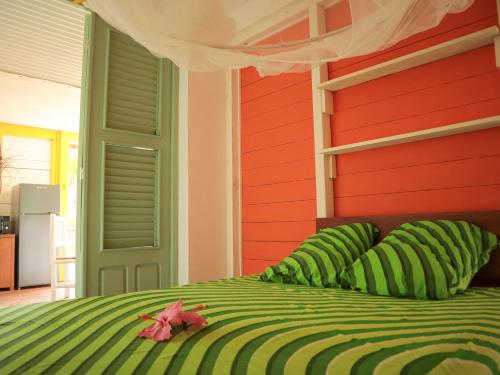 a bedroom with a green bed with a red wall at Villa-Coco in Grand-Bourg