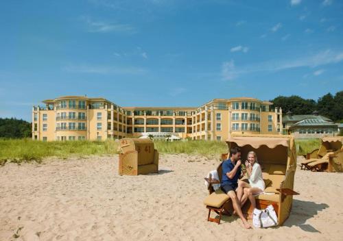 duas pessoas sentadas numa cadeira na praia em Hotel Gran BelVeder & Ostsee Therme Resort & Spa em Scharbeutz