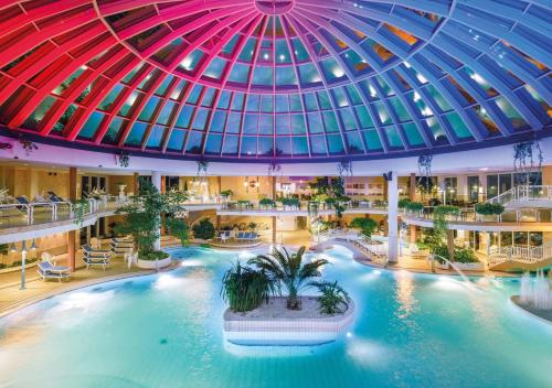 a large indoor pool in a building with a domed ceiling at Hotel Gran BelVeder & Ostsee Therme Resort & Spa in Scharbeutz