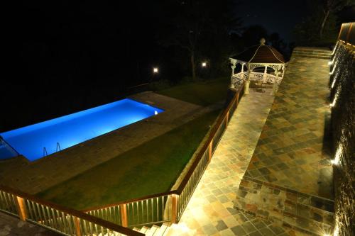une piscine la nuit avec un gazebo dans l'établissement Samsara Luxury Cottages & Spa, Chail Hills, à Kandāghāt