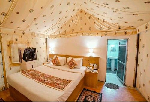 a bedroom with a large bed in a room with a ceiling at Hotel Kesar Dunes in Jaisalmer