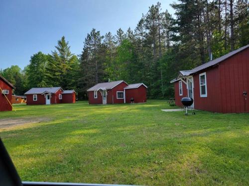 a group of red buildings in a field with a grill at cabin 3 in Steuben