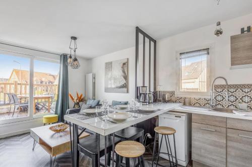 une cuisine avec une table et quelques chaises dans l'établissement Appartement Caima - Welkeys, à Cabourg