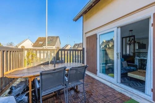 un patio avec une table et des chaises en bois dans l'établissement Appartement Caima - Welkeys, à Cabourg