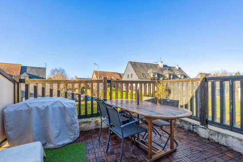 d'une terrasse avec une table et des chaises en bois sur un balcon. dans l'établissement Appartement Caima - Welkeys, à Cabourg