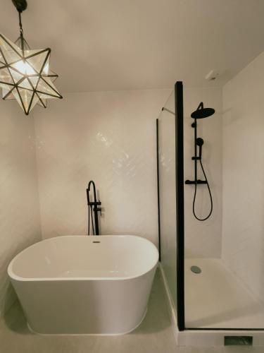 uma banheira branca na casa de banho com um chuveiro em Maison moderne proche CDG, Paris em Tremblay En France