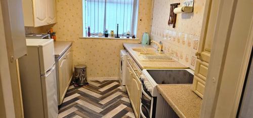 una pequeña cocina con suelo a cuadros en 2Bedroom Home away from Home en Mánchester