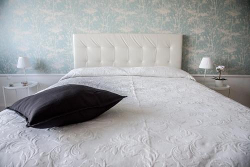 una camera da letto con un letto bianco e un cuscino nero di Acqua Holiday House a Taranto