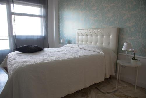 una camera con un letto bianco e una finestra di Acqua Holiday House a Taranto