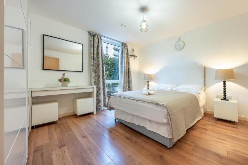 una camera bianca con letto e specchio di 2 Bed Flat in Brentford with Parking a Brentford