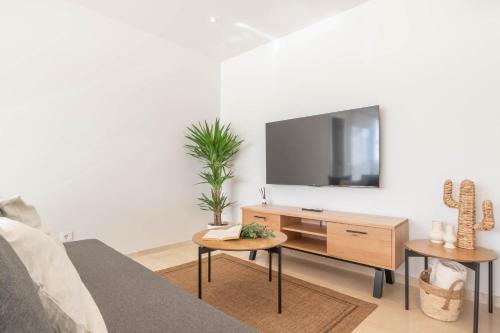 un soggiorno con TV su una parete bianca di Apartamento Marbelsun ll a Marbella