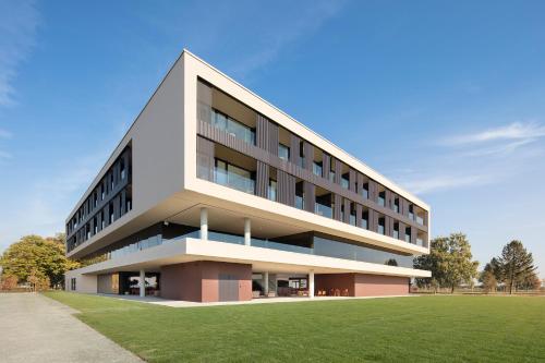 a building with a grass field in front of it at Hotel Materra in Osijek