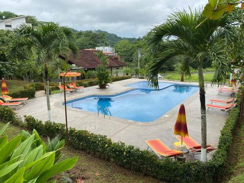a large swimming pool with chairs and palm trees at Punta Leona Beach Condos in Jacó