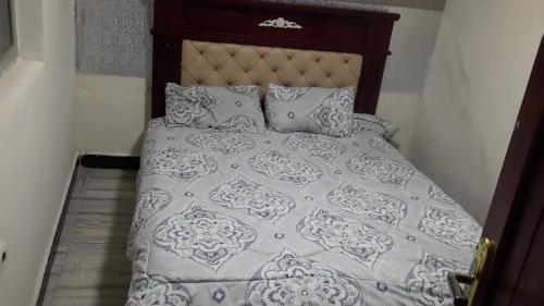 a bed with a gray and white comforter and pillows at M Pension in Addis Ababa