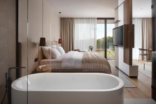a bedroom with a tub in front of a bed at Hotel Materra in Osijek
