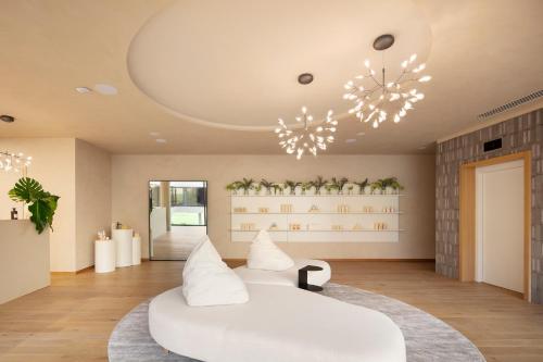a living room with a white couch and a chandelier at Hotel Materra in Osijek