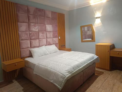 - une chambre avec un lit et une tête de lit rose dans l'établissement Home to home luxury apartments and suites, à Benin City