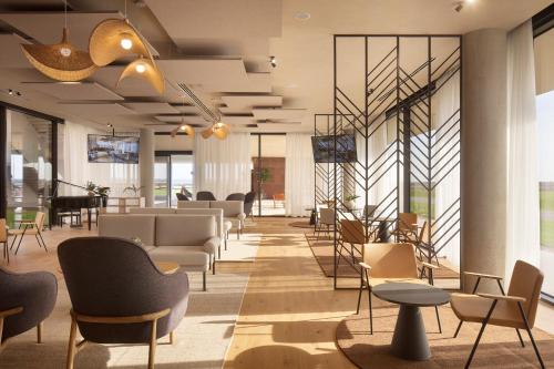 a lobby with chairs and tables and windows at Hotel Materra in Osijek