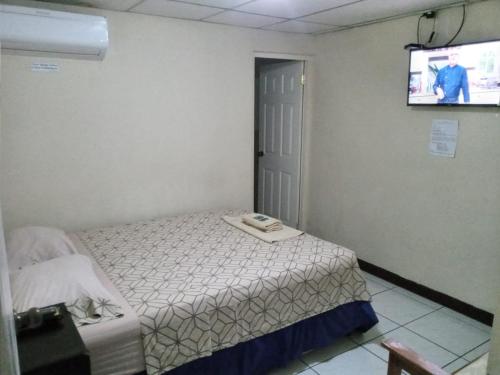 a small bedroom with a bed and a flat screen tv at Hotel Madriz in Managua