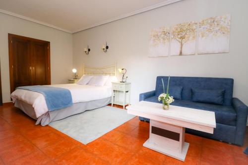 アレーナス・デ・サン・ペドロにあるHotel Rural El Retiro de San Pedro by RetiroRuralのベッドルーム(ベッド1台、青いソファ付)