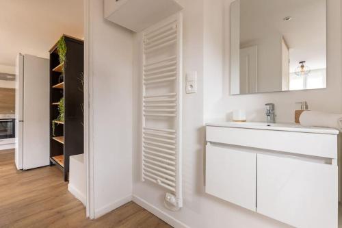 bagno bianco con lavandino e specchio di Vallière Adorable appartement parking gratuit a Metz