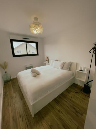 um quarto branco com uma grande cama branca e uma janela em Maison moderne proche CDG, Paris em Tremblay En France