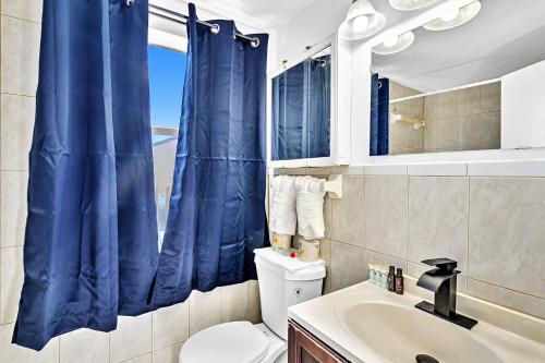 a bathroom with a toilet and a blue shower curtain at Coastal Sunset in Hollywood