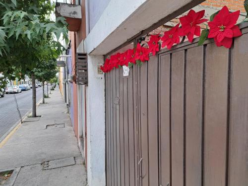 una valla con flores rojas al lado de un edificio en Habitación Chalini, en Cholula