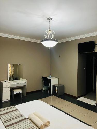 a room with a bed and a desk and a chandelier at TRMOTEL in Matola
