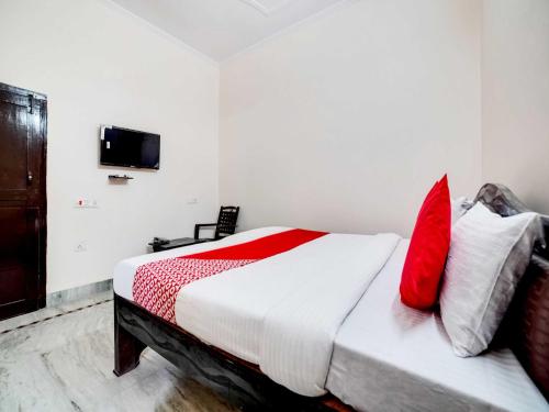 - une chambre avec un lit doté d'oreillers rouges et blancs dans l'établissement Shree Golju Palace, à Pantnagar