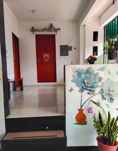 a hallway with a red door and a vase with a flower in it at Posada Nacha`n - Ka`an in Palenque