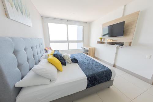 a bedroom with a bed with pillows and a television at Edificio Palmetto Beach Apto 1702 in Cartagena de Indias