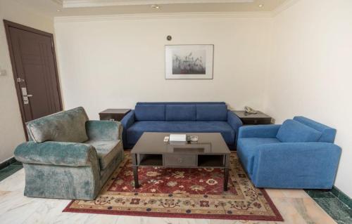 sala de estar con sofá azul y 2 sillas en Delmon Hotel Suites, en Yeda