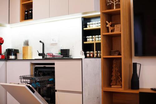 a kitchen with white cabinets and a tv at UrbanKop Vidik Residence in Kopaonik