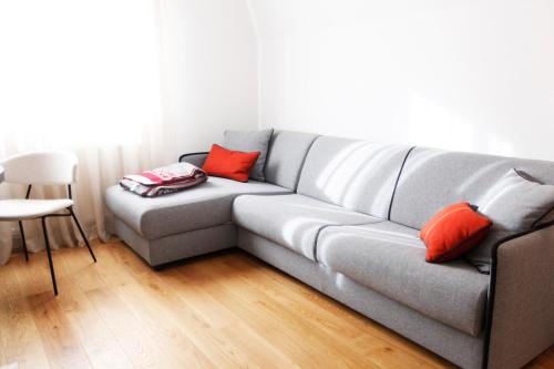 a gray couch with orange pillows in a living room at UrbanKop Vidik Residence in Kopaonik